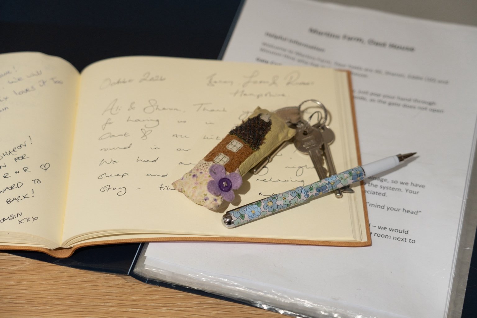 The handwritten guest book at The Oast, with the fabric house keyring and floral pen resting on its open pages